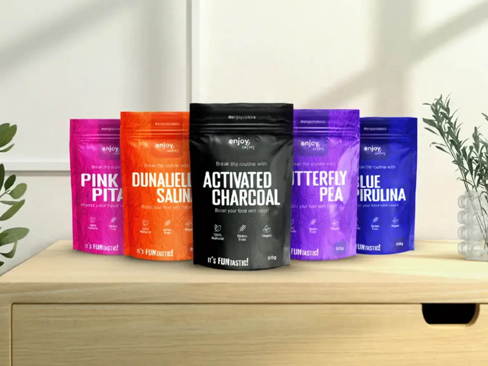 Projekt opakowań Enjoy Colors dla naturalnych barwników spożywczych w saszetkach, pokazujący serię kolorowych produktów na drewnianym blacie