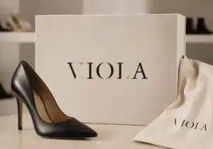 Propozycja logo VIOLA dla sklepu obuwniczego, zaprezentowana na pudełku i opakowaniu obok czarnej szpilki.